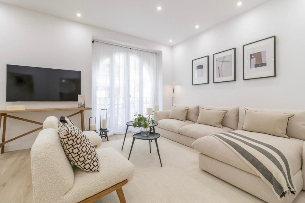 Reforma salón grande terminada en Madrid – suelo laminado, sofá moderno y diseño abierto luminoso